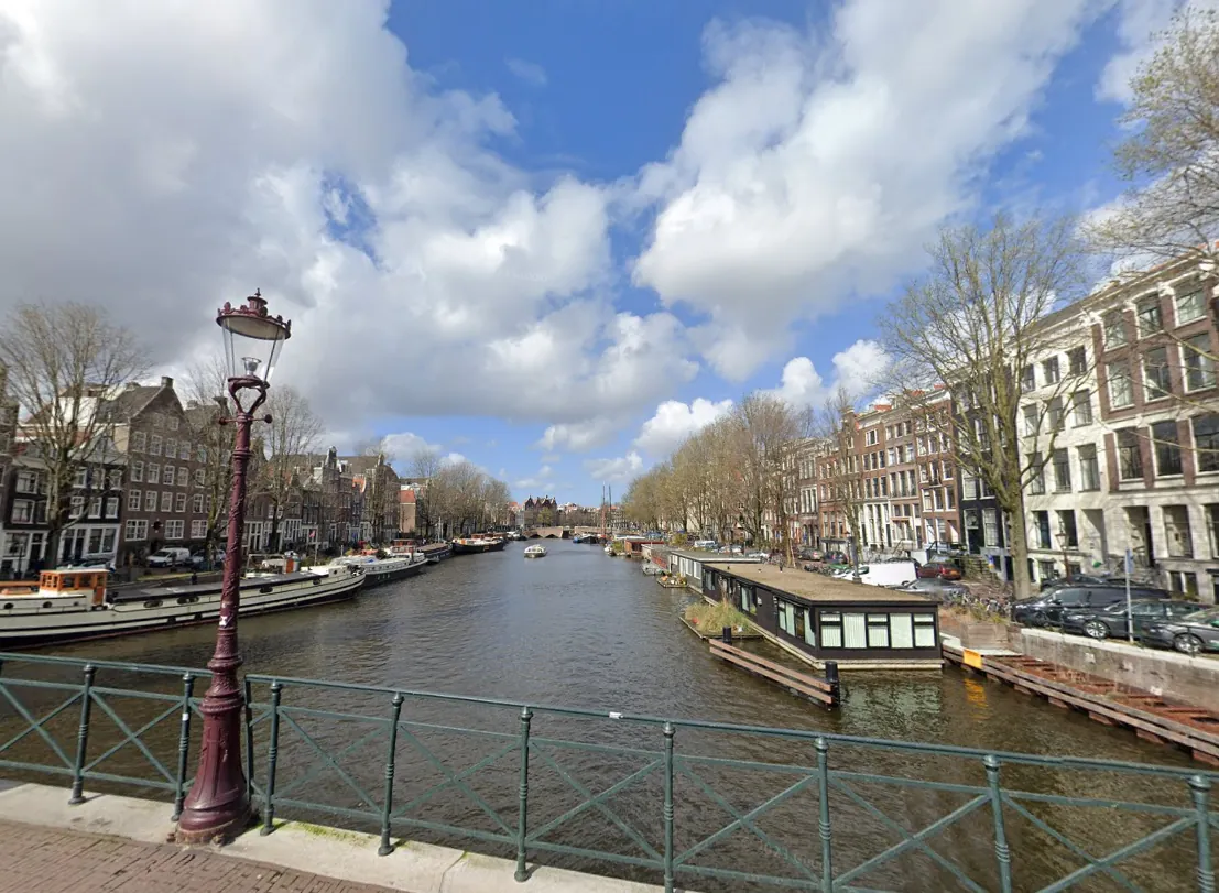Amsterdam canal bordered by quay walls and historic buildings.